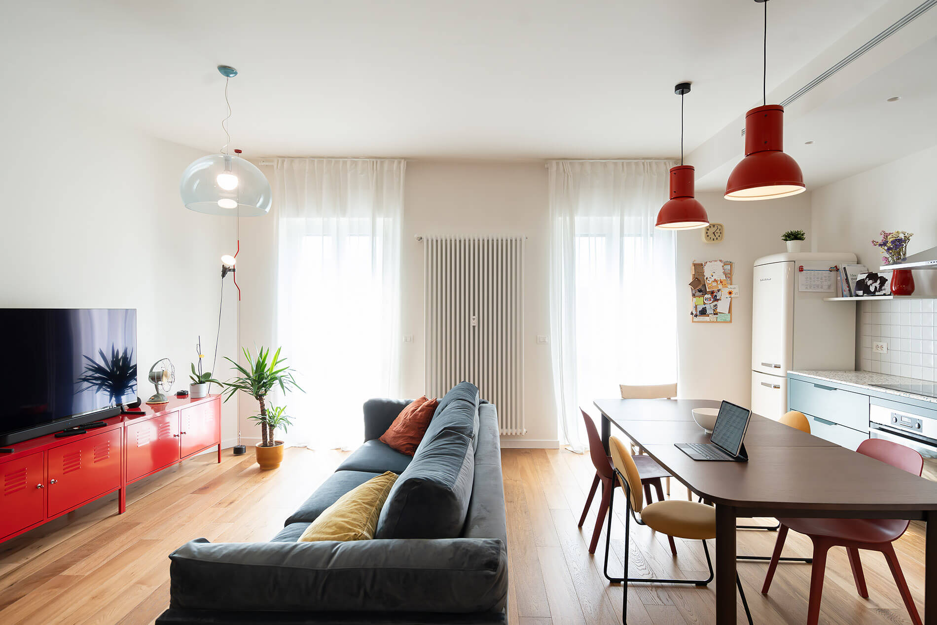 inloco lab architetti Asti appartamento ristrutturato vista cucina con basi in metallo lampade industriali rosse, divano con penisola free stand arredo in cartone mobile tv rosso in metallo stile industriale